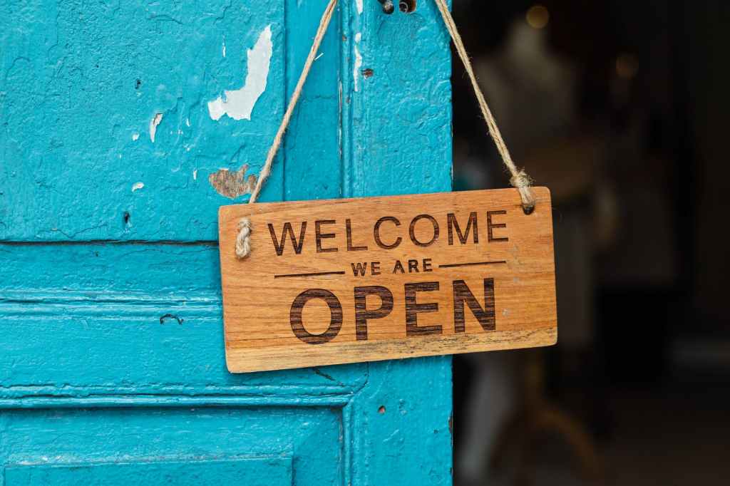 a blue door with a "Welcome. We are open" sign.