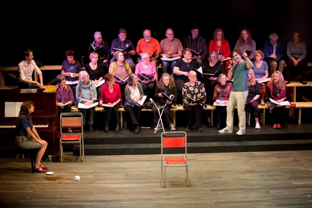 Choir sitting on risers. A pianist is in front.